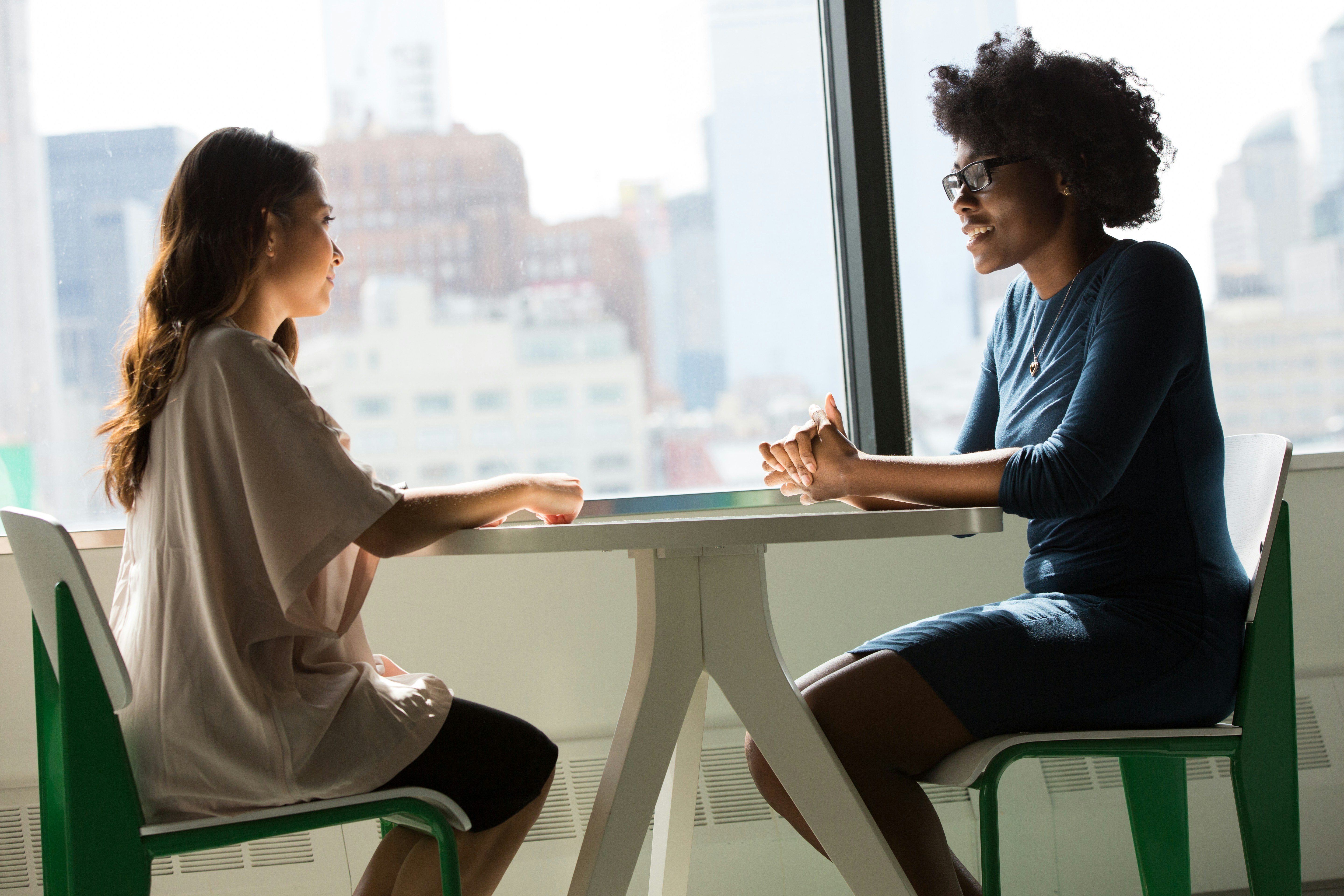Two women sitting across from each other at a table, engaged in a professional conversation during an informational interview.